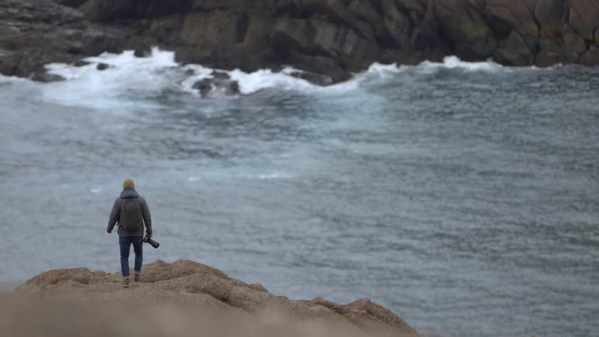 Man approaching the ocean with a camera in hand