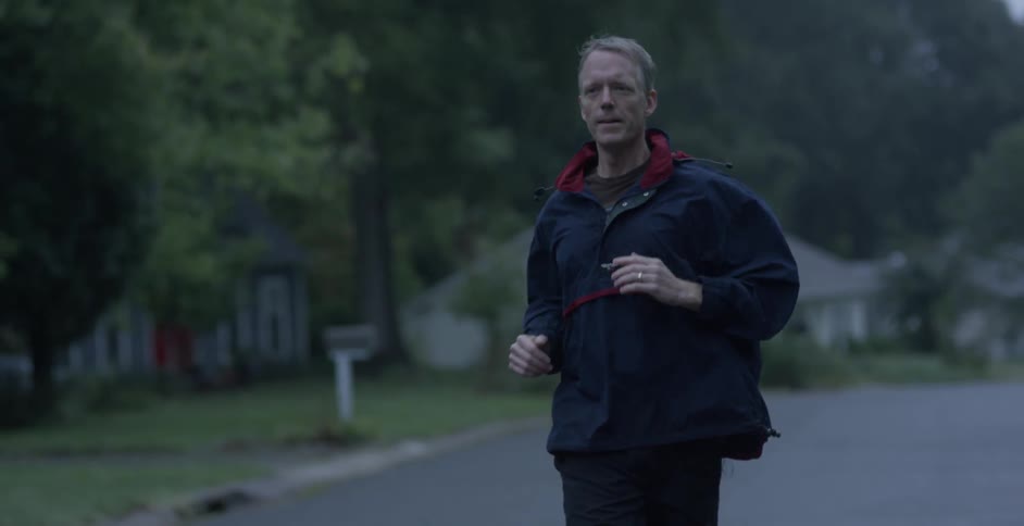 Man running down a street in a neighborhood
