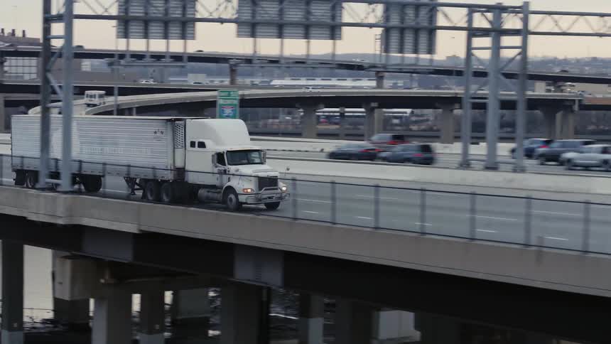 Semi truck driving down a highway bridge