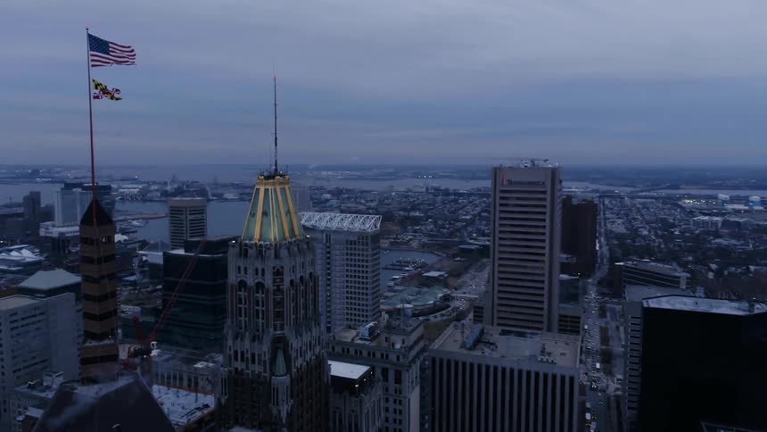 A us flag flies atop a building in a city at dusk