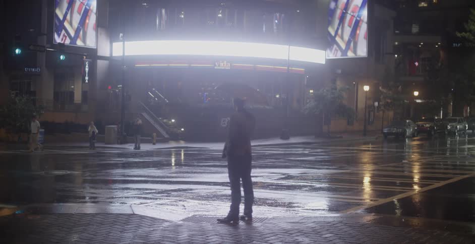 A man holding an umbrella stands near a crosswalk
