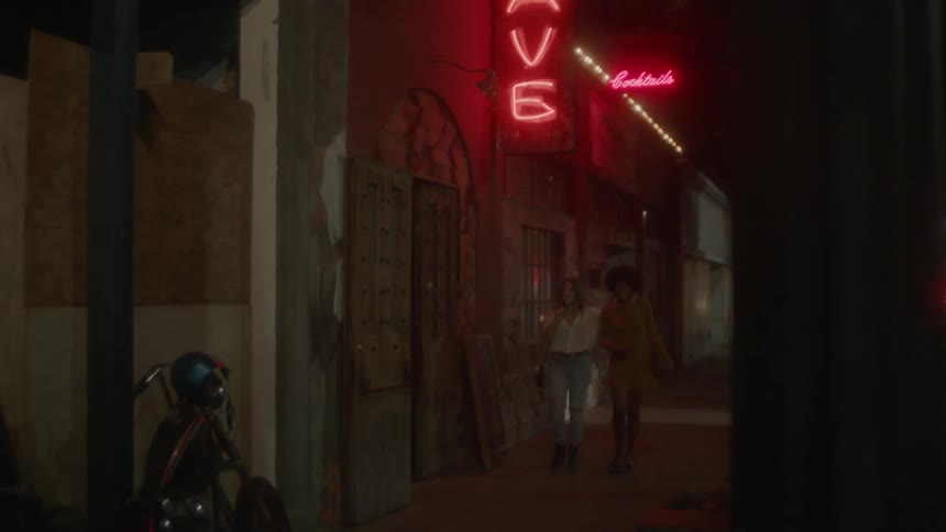 Two women holding hands walking down a city street at night
