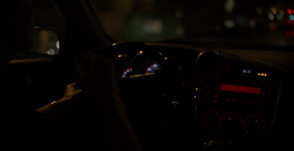 A car is driving in the rain at night