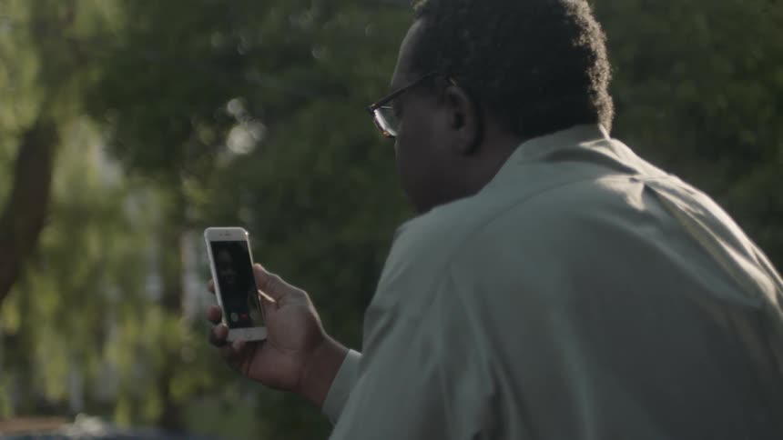 A man is sitting outside using his phone