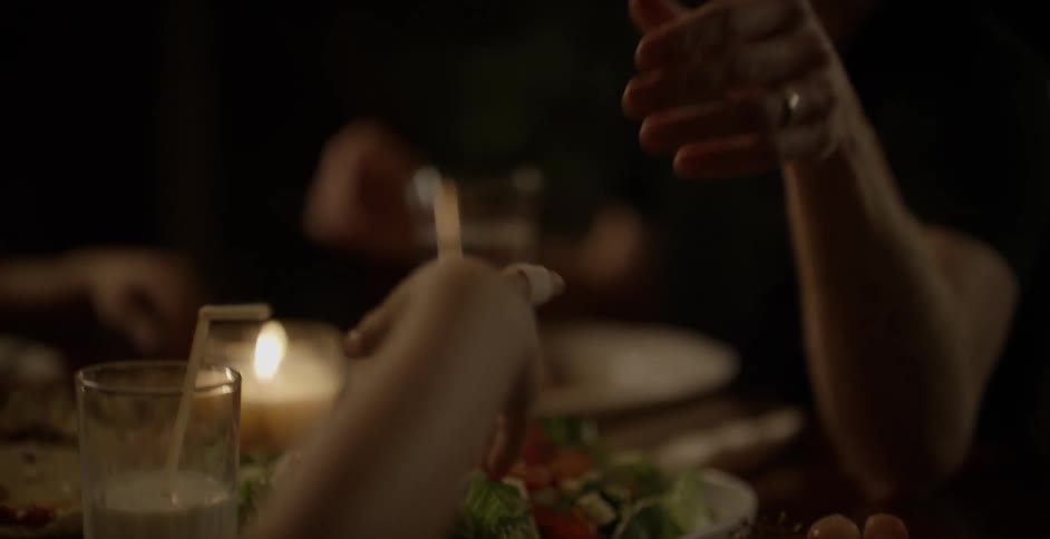 People holding hands in prayer at a candlelit dinner table