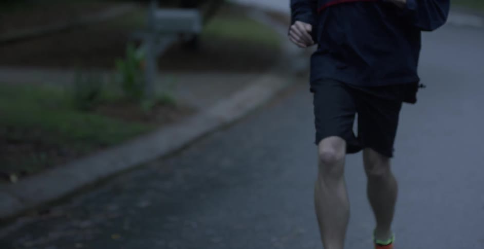 A man is jogging outside wearing yellow sneakers