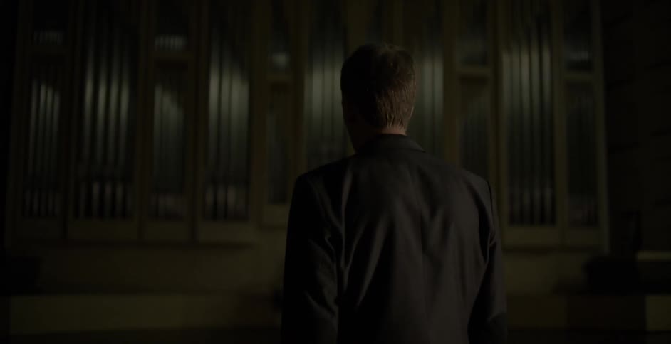 A man walks around in a darkened concert hall