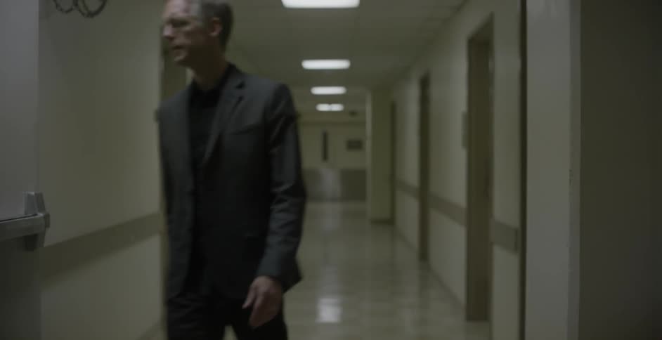 A man walking down a school hallway and leaving