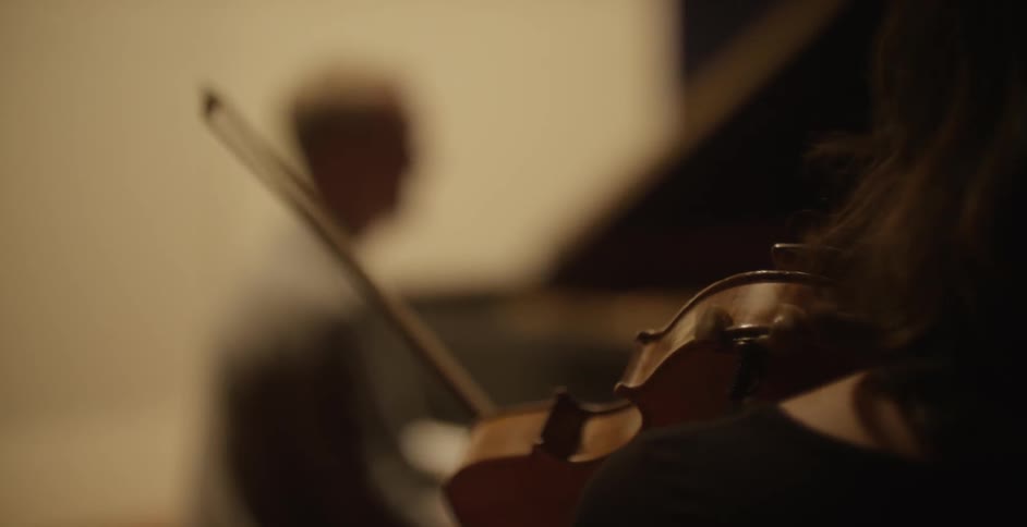 A woman holds a violin at the ready