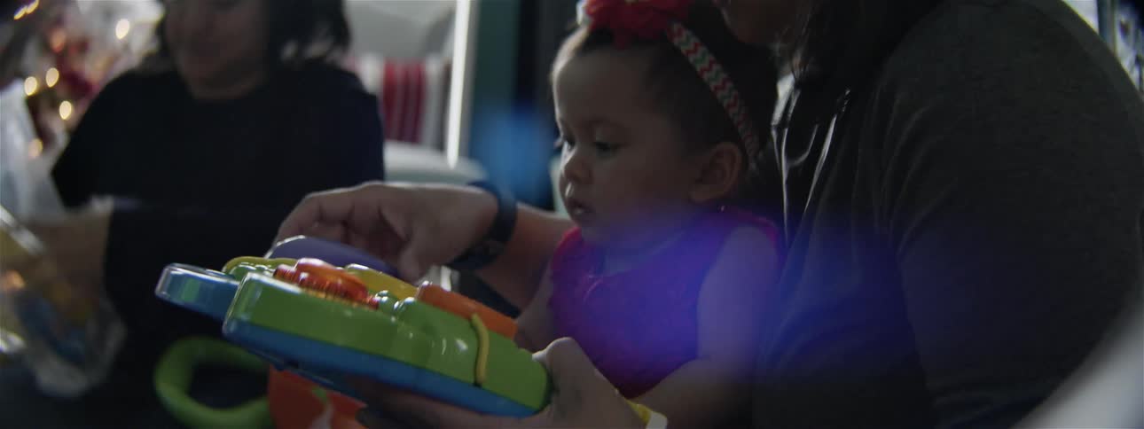 Women watch as a child plays with a toy