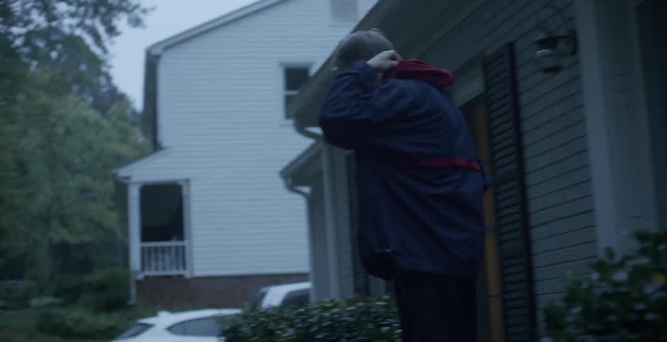 A man exits his house, locks the door, and then walks down the street