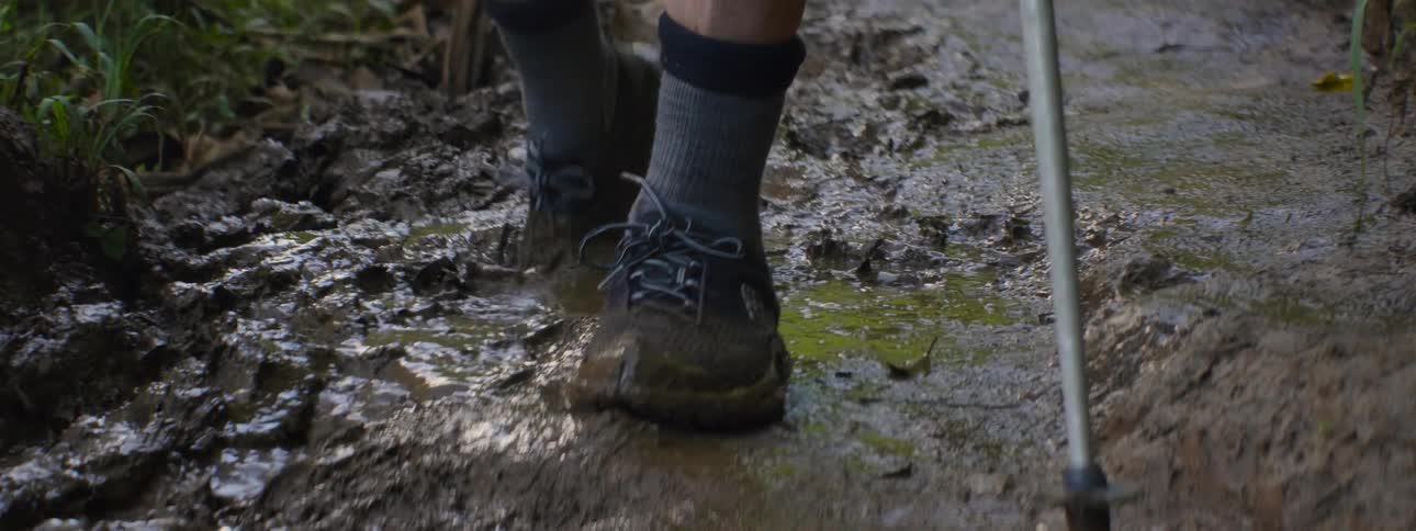 Person splashing through mud holding two walking sticks
