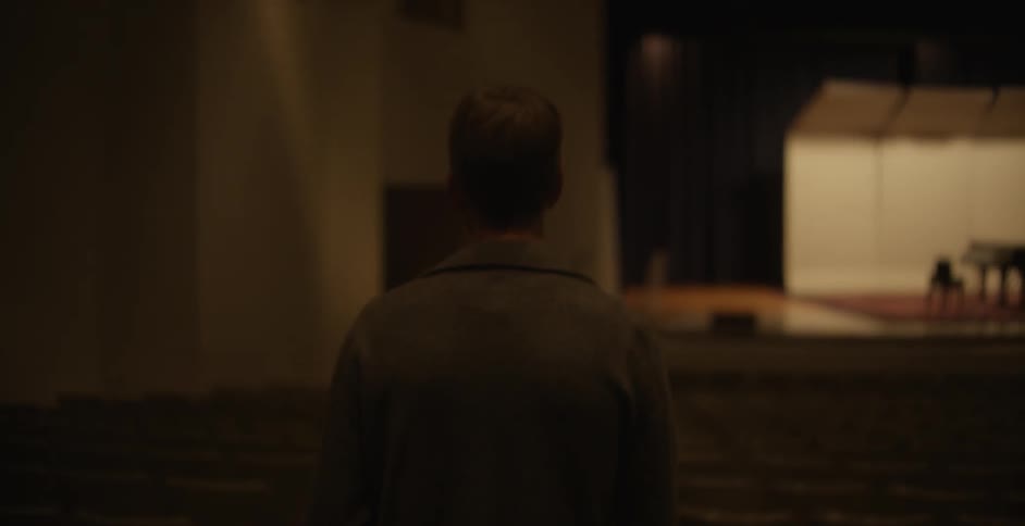 A man approaches a stage in an empty auditorium