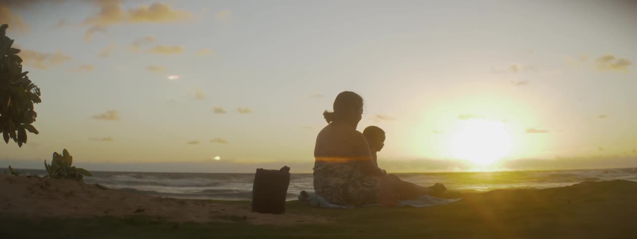 Woman and child sitting on the beach at sunset