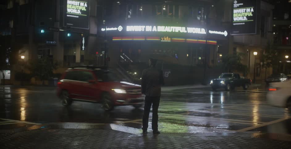 A man holding an umbrella walks up to a crosswalk