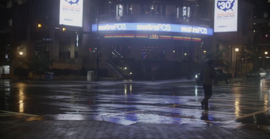 Person stands on a busy street corner at night