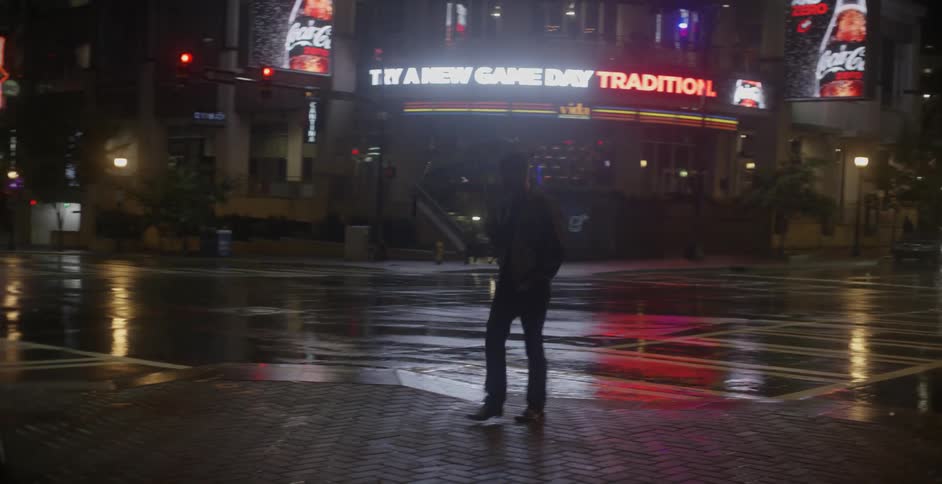 A man holding an umbrella crosses a crosswalk