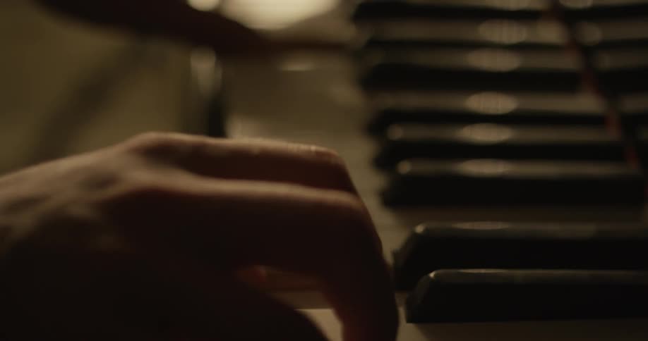 A person is playing a piano in a dark room