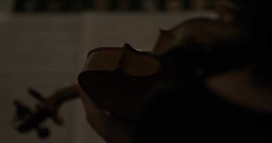 Person playing a violin in a dimly lit room