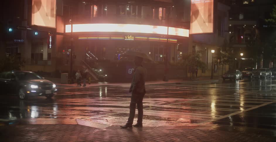 A man holds an umbrella at a crosswalk