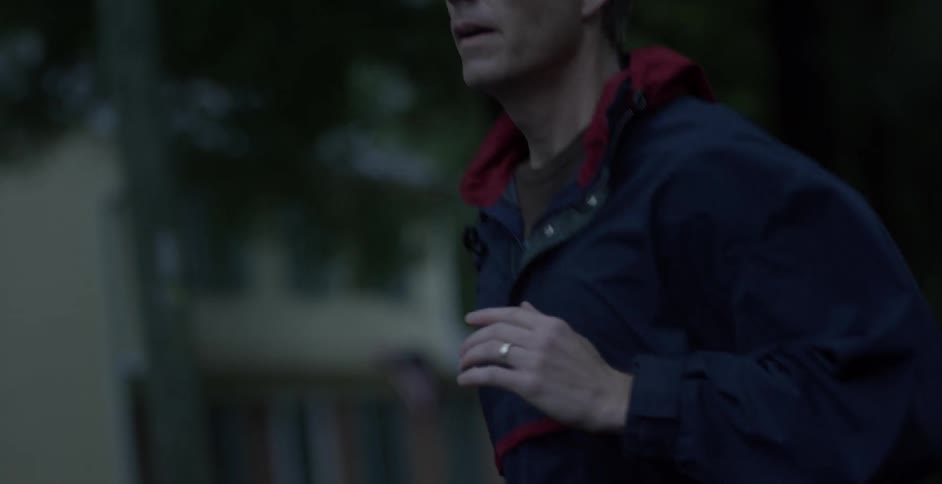 A man in a blue jacket jogs down the road