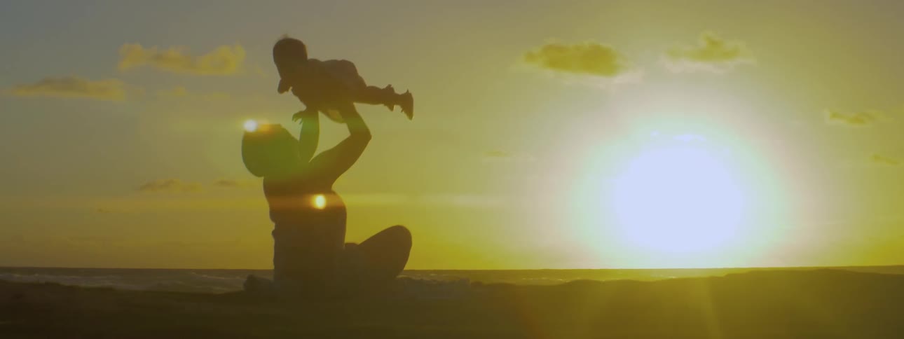 Woman holding a child up sitting on a beach