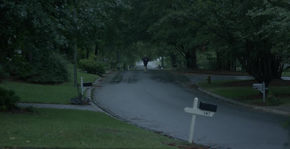 Man running down a street in a neighborhood