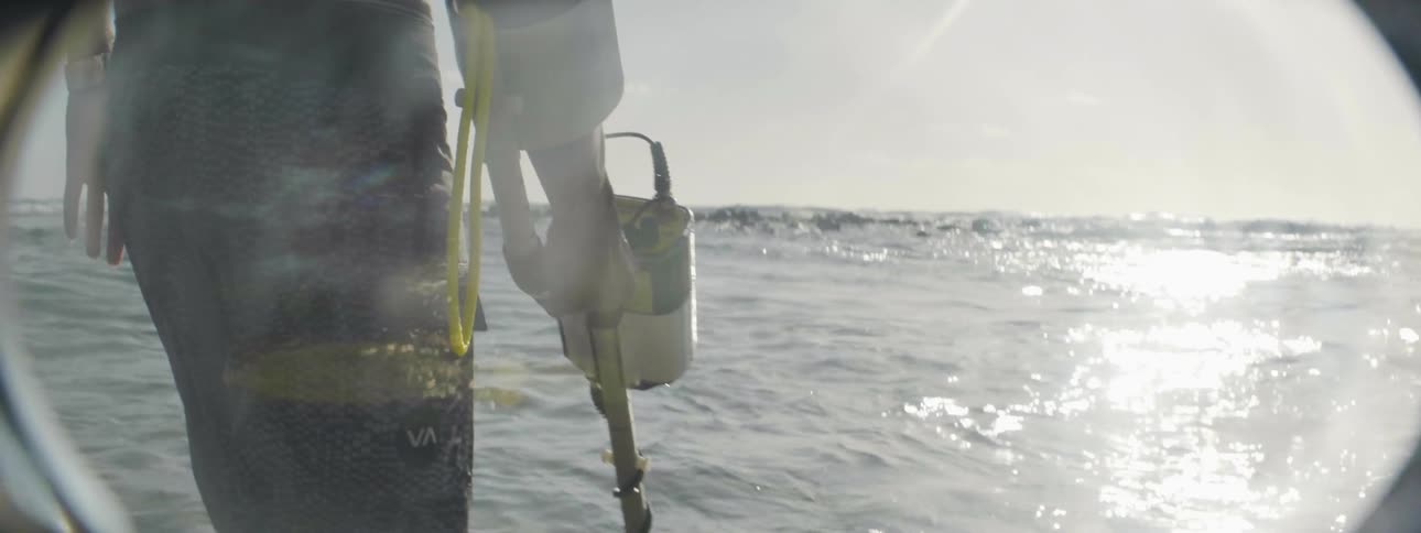 Person in the ocean with a metal detector on a sunny day