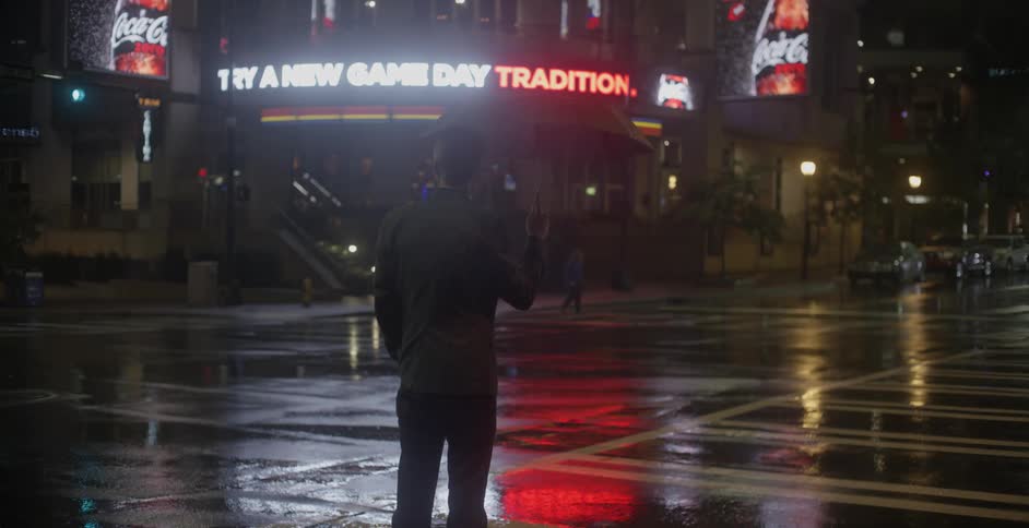 A man stops at the intersection as the cars pass