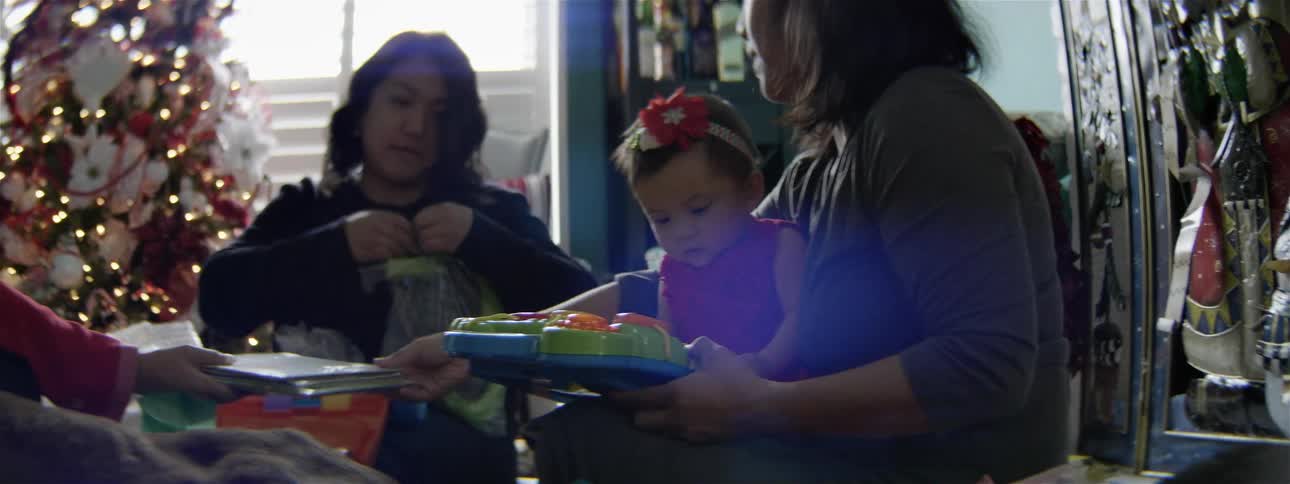 Two women open presents for a small child