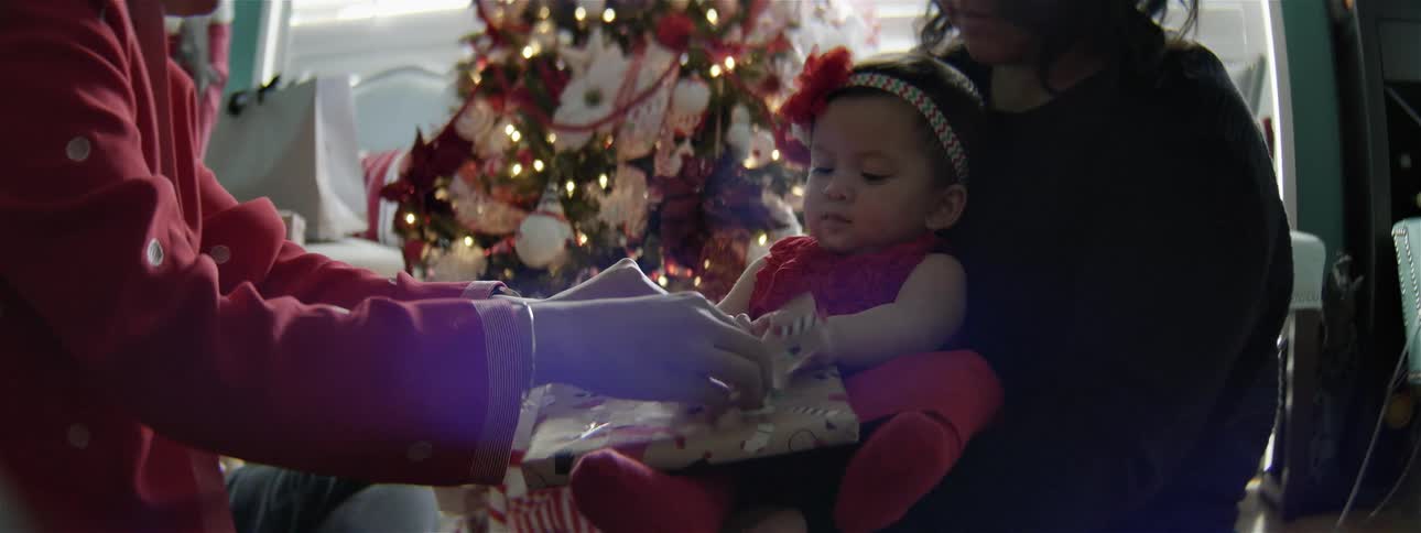 A baby is opening up a christmas present