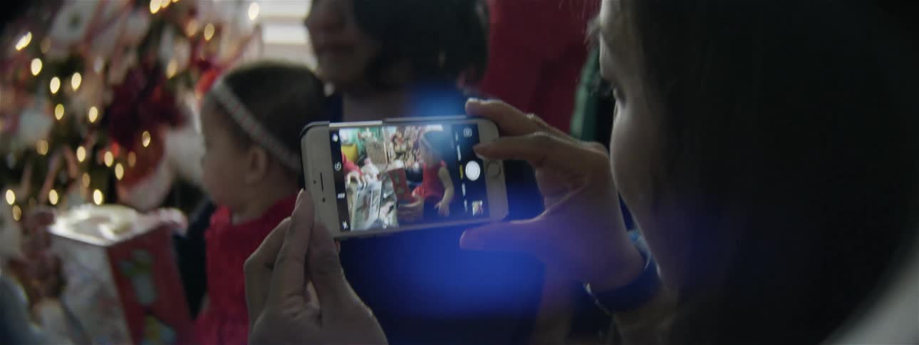 A person takes pictures of a baby at christmas
