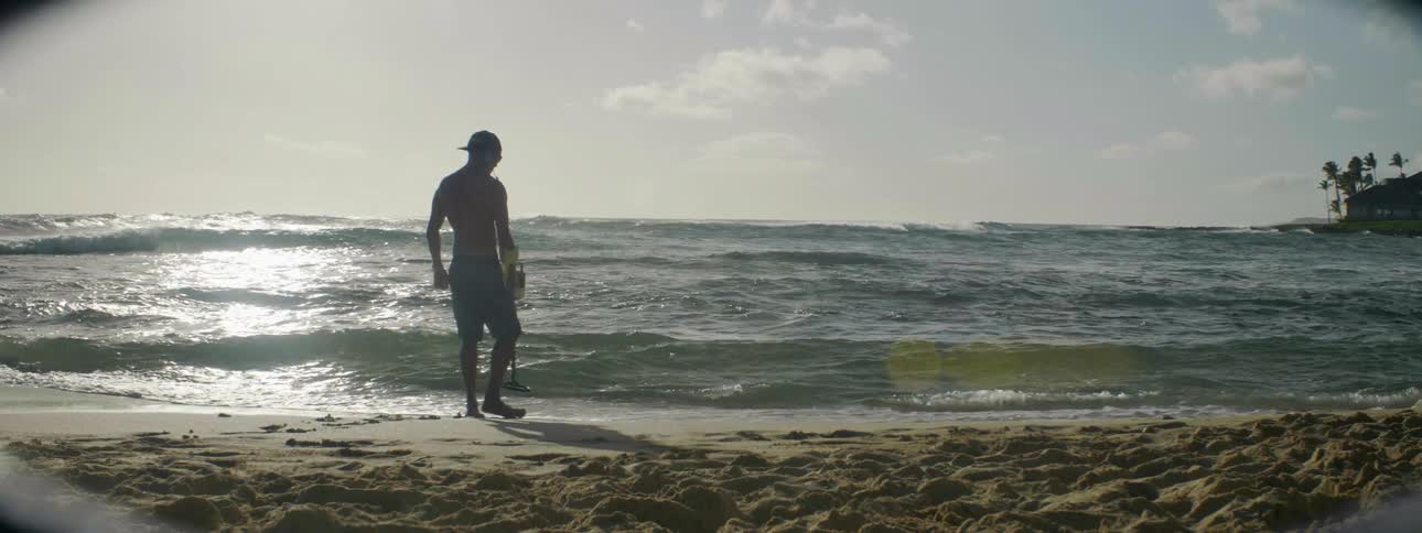 A man uses a metal detector on the beach