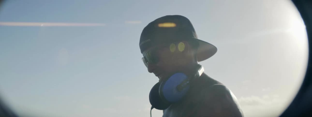 Man wearing headphones looks out at the water on a sunny day