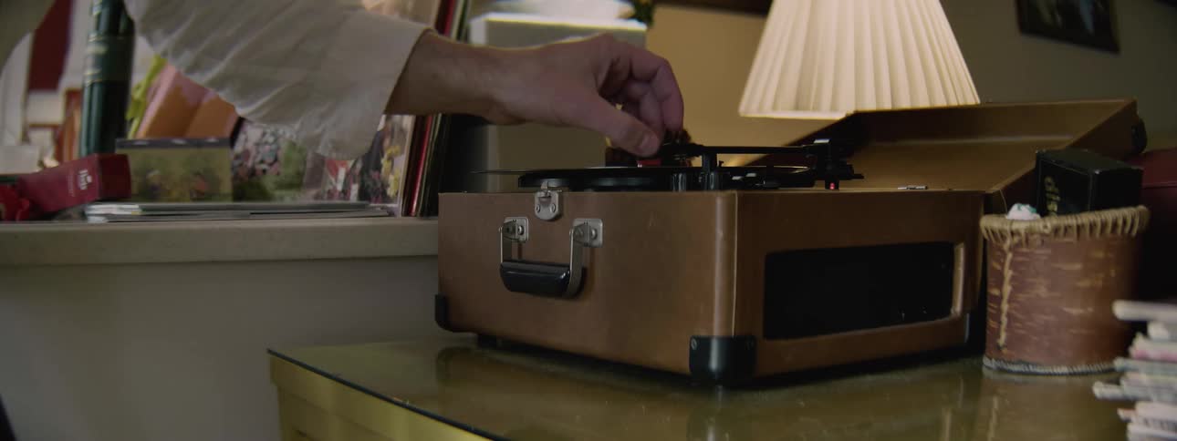 A man opens a turntable case and plays a record