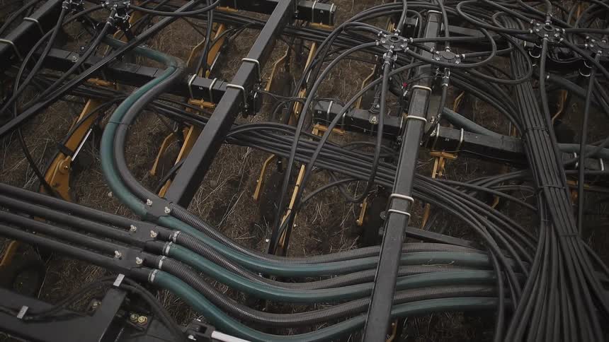 Many wires are on the back of this farm vehicle