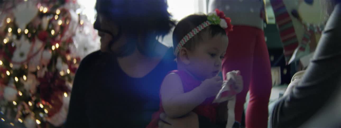 A woman holds a baby dressed in red at christmas