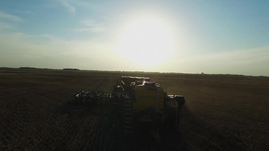 Tractor plowing a large piece of farmland on a sunny day