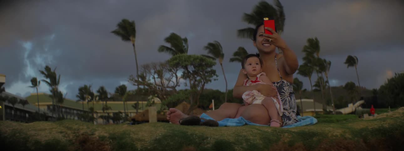 A woman holds her baby on the beach and takes pictures