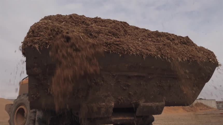 A backhoe loaded with composted organic material is backing up
