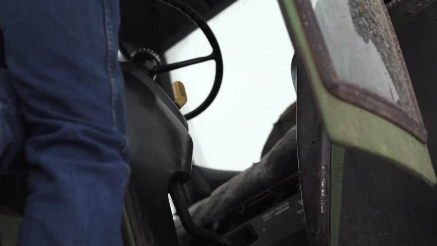 A man climbs into his farm vehicle
