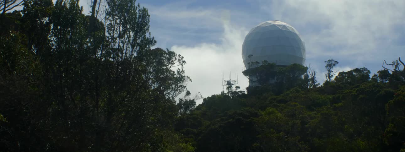 A dome sits in the sky by the forest