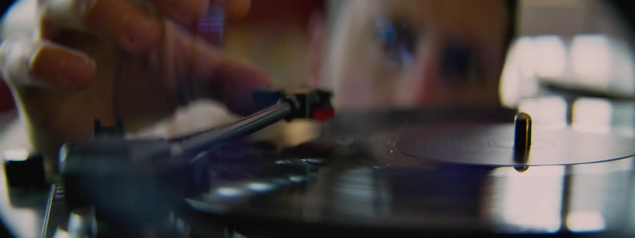 A man puts the tone arm on an lp on a record player to begin playing it