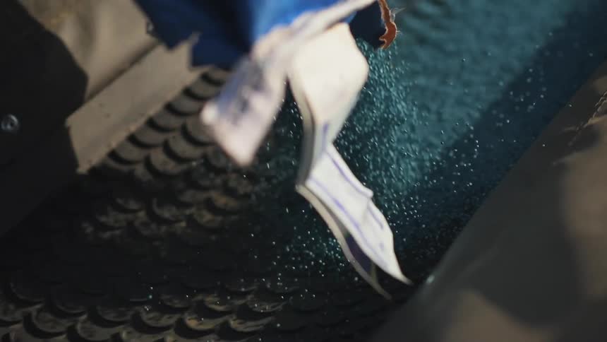 Blue pellets being poured onto a quickly moving conveyor belt