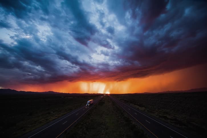 Cars speeding on a country highway at sunset