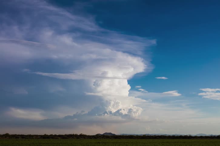 A storm cloud builds as the sun sets