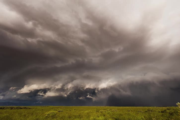 A storm rolls over grassy plains