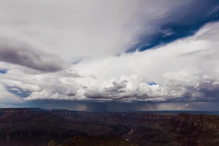 White puffy clouds roll over a canyon