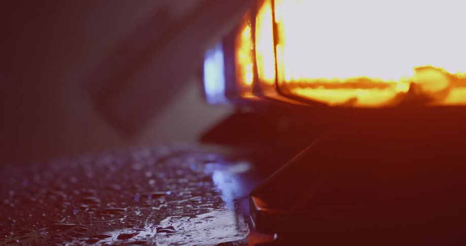 Close up of headlight flickering and rain on a car hood