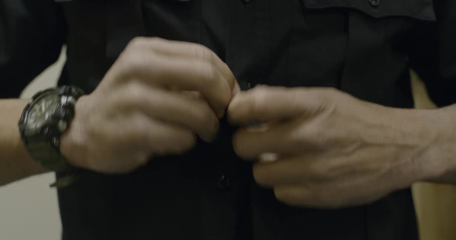 A man buttoning up his shirt